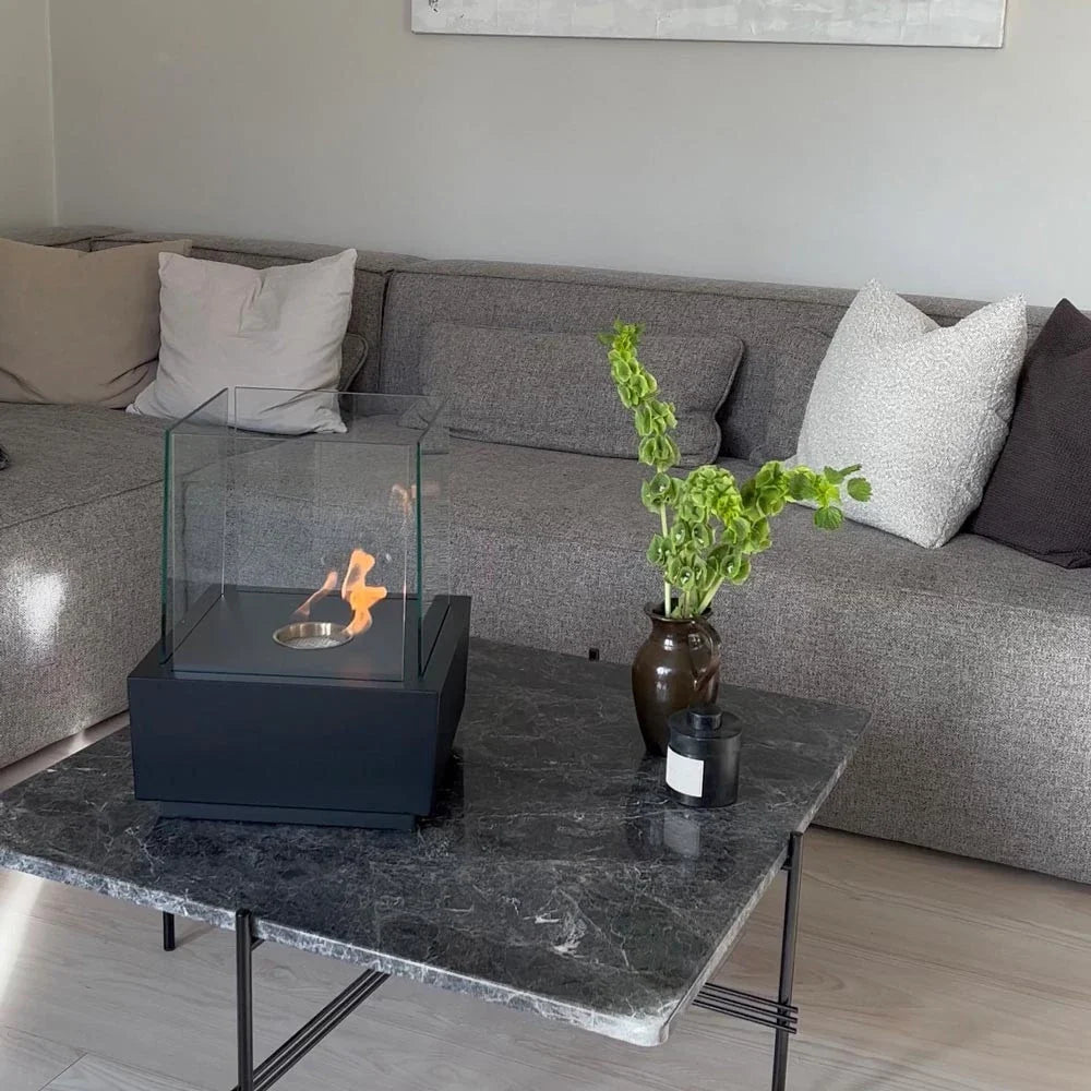 Elegant bioethanol fireplace with detachable glass top used as a tabletop fireplace, lit, on a coffee table
